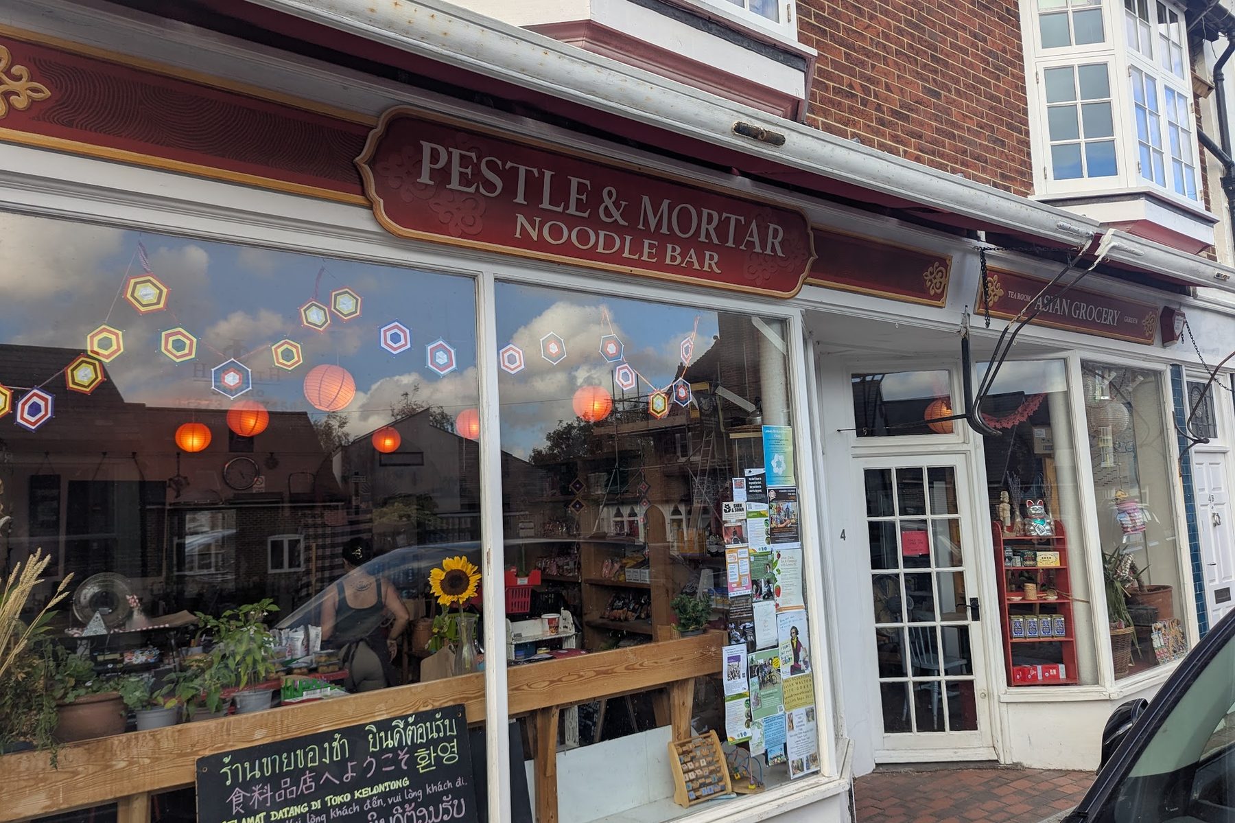 The Pestle & Mortar shopfront on Lansdown Place, with a gold-lettered Noodle Bar sign, a chalkboard by the door and paper lanterns in the window.